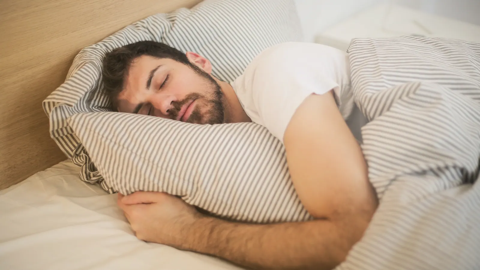 Hombre durmiendo plácidamente abrazando una almohada