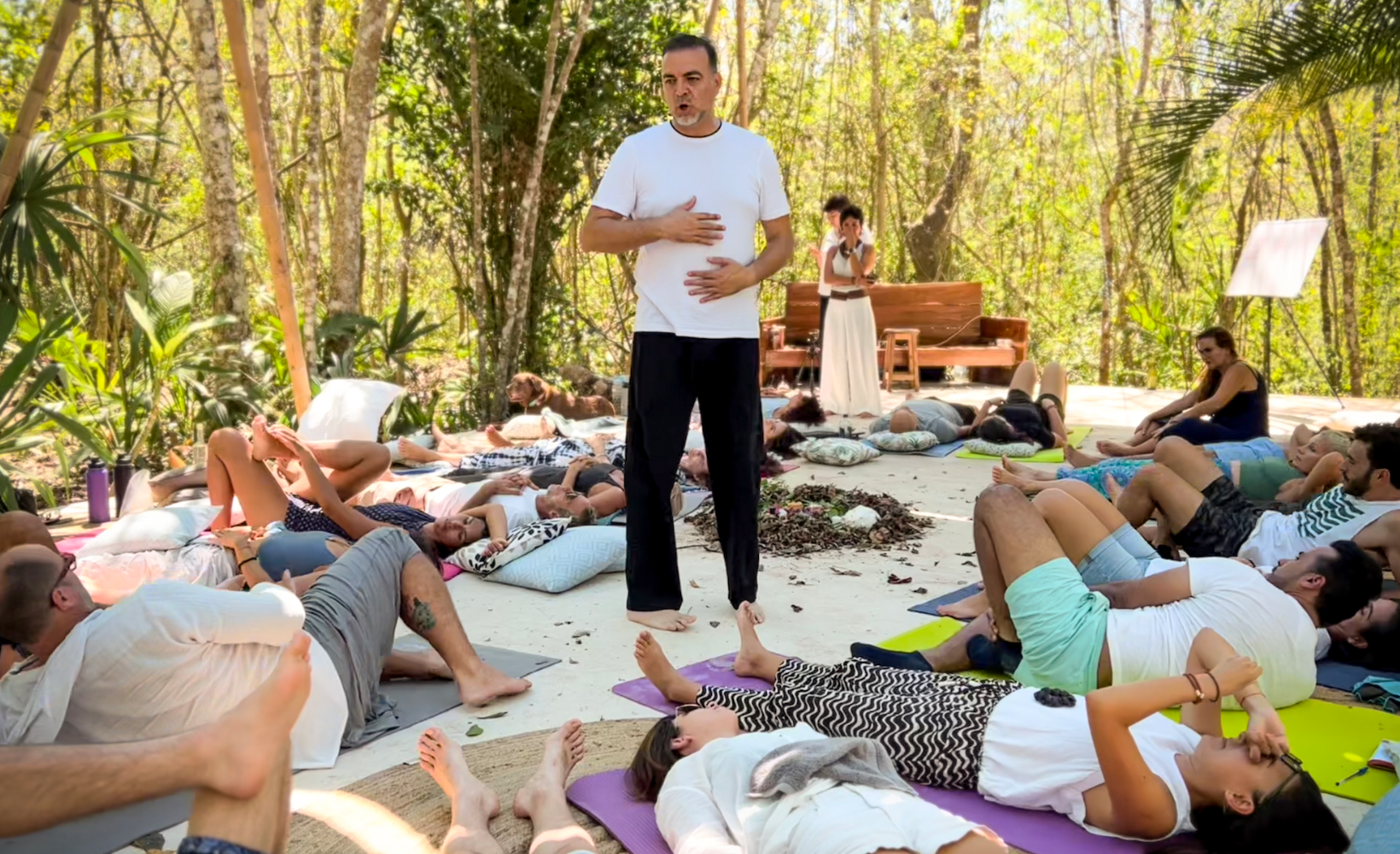 Rafael Yedid guiando práctica de respiración en retiro al aire libre, con participantes recostados conectando con su energía y emociones